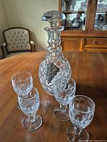 Decanter with stopper and four glasses on table