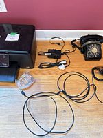Printer, rotary phone, power adapter and cables on floor