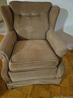 Front view of upholstered armchair showing tufted back, cushion, skirted base