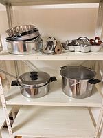 Shelved view showing stock pots, stacked pans, rolling pin, cookie cutters in star pan