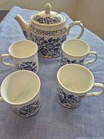 Teapot and four mugs displayed together showing pattern and quantity
