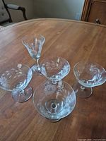 Group of four coupe glasses and one cordial glass showing pattern and form