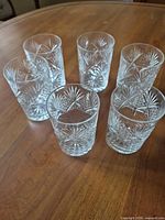 Six clear cut glass tumblers grouped on table