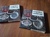 two boxed silverplated coaster ashtray sets displayed on wood surface