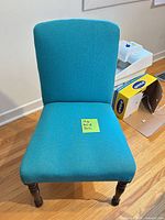 Front view of teal armless accent chair on wood legs