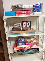 Stacked board games on upper shelf: Probe, Chess, Chinese Checkers, Clue, Ouija, Meccano