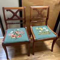 Front view of both mahogany chairs showing carved backs and floral needlepoint seats