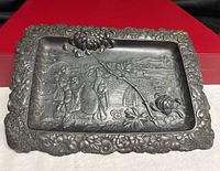 Full view of metal tray showing entire relief scene and floral border