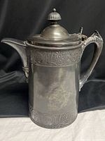 Full view of silver plated pitcher showing body, handle and lid