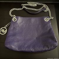 Front view of plum leather Michael Kors shoulder bag with chain strap and MK charm