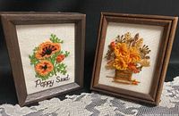 Both framed floral crewel embroidery pieces side by side