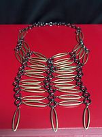 Front view showing full bib design, two-tone metal ovals, drop accents, chain clasp