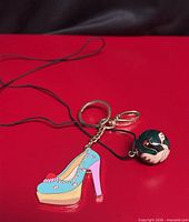 High heel keychain and swan pendant together on red background