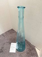 Full view of tall blue glass bottle standing upright