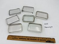 Seven clear glass rectangular paperweights with ruler for scale