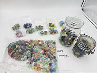 Lot overview showing two glass jars of marbles, large zip bag and small bags