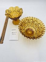 Footed compote and ruffled bowl side by side with ruler for scale