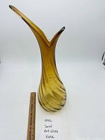 Full view of amber swirl art glass vase with ruler for scale