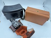 Camera, black bag, tan case, brown fitted case visible