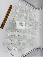 All 33 etched wheat glasses arranged on surface with ruler for scale