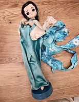 Full view of doll showing outfit and wooden base