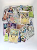 Overhead view of assorted Pokémon cards showing fronts, including multiple Pikachu variants and a Tag Team GX card, some in sleeves