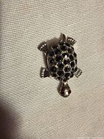 Front view of silver-tone turtle showing black stones and red eyes