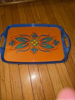 Top view showing orange surface, floral motif and blue rim