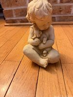 Front view of seated child with bunny figurine, full piece shown