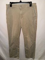 Full front view of tan khaki pants on hanger