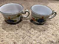 Two Italian floral ceramic tea cups side by side