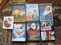 All media items arranged on rug—six DVD cases, one loose DVD, one VHS