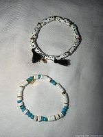 Both bracelets laid out on fabric showing design, beads, tassels and Pura Vida charm