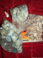Overview of three bags of assorted craft stones on red background