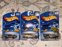 Front view of three sealed Hot Wheels cars on blister cards numbered 112, 219, 093