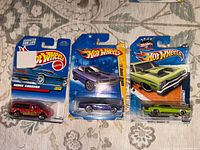 Front view of three Hot Wheels cars in packaging