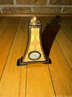 Front view of Eiffel Tower-shaped clock showing harlequin pattern, dial, and finial