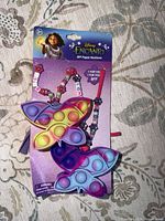 Front of sealed package displaying two butterfly popper necklaces and Encanto branding