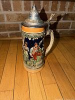 Full view showing stein height, pewter lid, handle, relief decoration