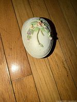 Top view of closed porcelain egg dish showing applied floral bouquet and molded border