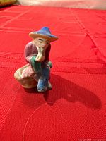 Front view of multicolored ceramic scholar figurine on red surface