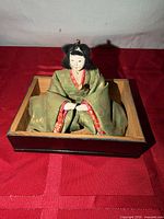 Front view of hina doll seated in display box showing full costume and facial details