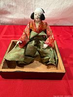 Front view of Hina doll seated in tray showing attire and head