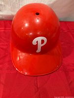 Front view of red plastic Phillies helmet showing logo