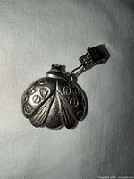 Front view of pewter ladybug pendant showing wing spots and clip