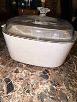 side view of white square casserole dish with glass lid