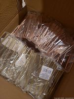 Sealed gold-tone and copper-tone wire holders stacked in shipping carton