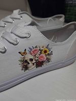 Close side view showing skull and floral graphic on white canvas