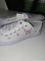 Side view of sneaker showing butterfly print and tag attached