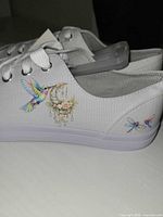 Side view showing hummingbird and floral graphic on white canvas sneaker